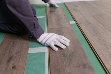 Worker lays the laminate in the apartment. Laminate is lying on the floor in the apartment, the...