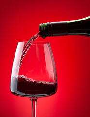 Red wine pouring from bottle into glass