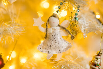 Obraz premium Close up of holidays location with angel toy and garlands on white yellow Christmas tree