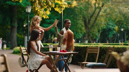 Happy and excited two pretty ladies have a meeting time with a black and woman and blonde hair female they hugging each other at the cafe