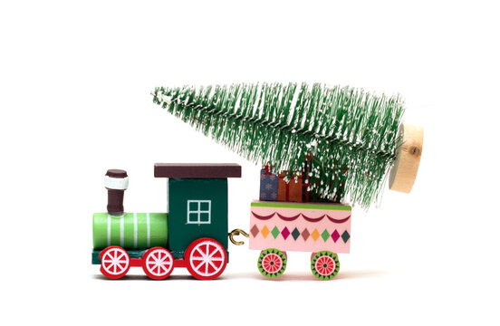 A toy locomotive is carrying a Christmas tree. Feast of the Nativity of Christ. Isolated photo for design.