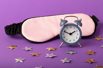 Mask for sleep and alarm clock near it.Gold and silver stars around.Circadian rhythms concept.