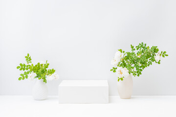 Empty white box and flowers in a vase on a light background. Mockup banner for display of advertise...