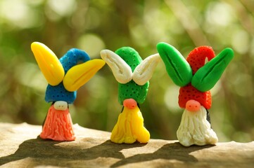 Figures of Easter gnomes with ears made of plasticine on a colored background.