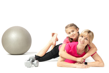 Fototapeta na wymiar Pretty young woman and her daughter lie on a yoga mat in a fitness studio looking at the camera and smiling isolated on a white background.