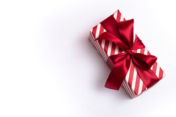 Striped gift box with a red bow on a white background. close up.