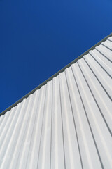 Fototapeta na wymiar Textured white metal structures diagonally against a blue sky.