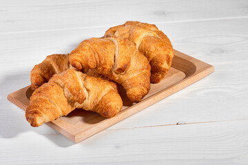 Golden brown butter croissants with shadow on the white wooden background, copy space