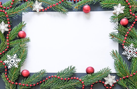 A Christmas or New Year's card. Copyspace. A place for your congratulations or advertising. The frame is made of spruce branches, decorated with red balls and snowflakes. High quality photo
