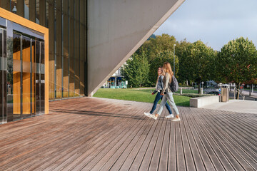 Two college classmates entering the university to attend classes on a sunny day.