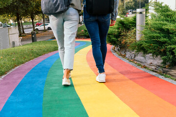 Two women walking along a road painted with the colors of the rainbow.