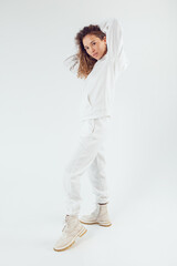 Attractive woman with thick curly hair in a white suit of hoodies and sweatpants. Mock-up.