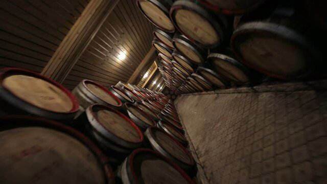 A Wine Cellar. Storage Room for Wine in Bottles and Barrels. Old wine in a dark underground vault. Wooden oak whiskey, wine, cognac, brandy or beer barrels. Bottles on wooden shelves. Rotate