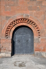 Fototapeta na wymiar Beautiful metal gate in a stone wall. The arch of the gate is stone.
