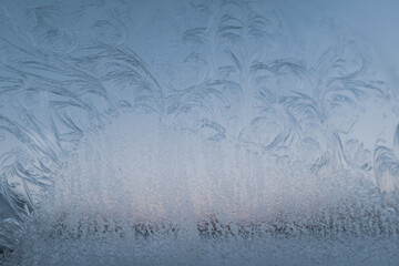 Fancy patterns drawn on a frosty winter day. Frost texture from the ice crystals on the glass of the window, strong cold concept, copy space for your design or text. Snow patterns on the glass