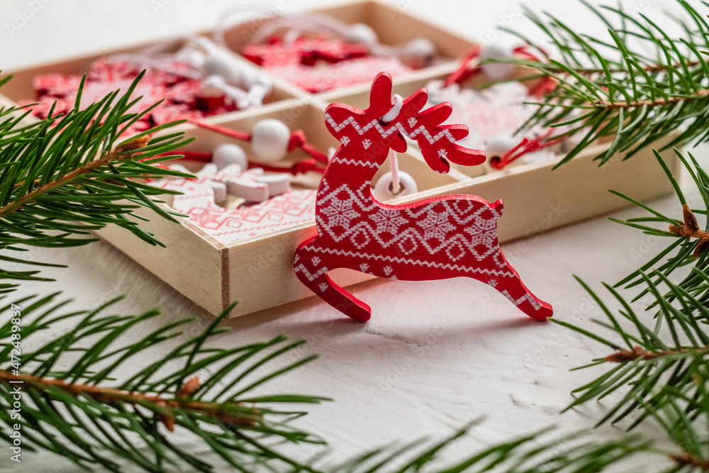 Wall mural Christmas gift box with wooden deer toys and green fir tree branches. Christmas red wooden deer. Christmas decor.