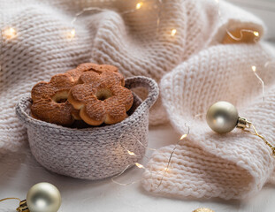 Fototapeta na wymiar Christmas shortbread cookies near a white knitted blanket. Flower shaped cookies in a crocheted light basket.