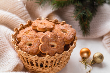 Christmas shortbread cookies in a wicker basket and branches of a Christmas tree. Flower shaped shortbread.