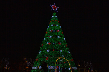 big green christmas tree and city decorated in the background