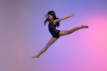 young gymnast athlete performing jumps, training for competition, colorful background in a studio.