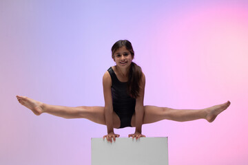 child athlete gymnast performing gymnastic exercise on top of apparatus, training for competition, colored background in a studio