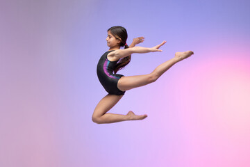 young gymnast athlete performing jumps, training for competition, colorful background in a studio.