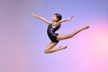 young gymnast athlete performing jumps, training for competition, colorful background in a studio. - obrazy, fototapety, plakaty