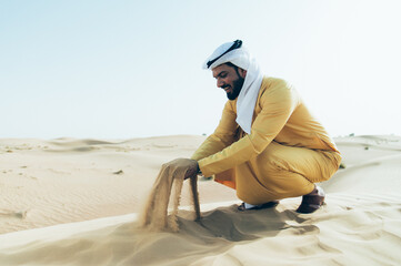 Man wearing traditional uae clothes spending time in the desert