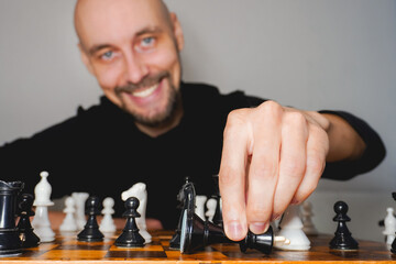 Bald man wearing beard playing chess on board. Strategy and competition concept. Selective focus
