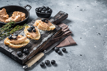 Toast with Foie gras pate and fresh blueberry on wooden board. Gray background. Top view. Copy space - obrazy, fototapety, plakaty