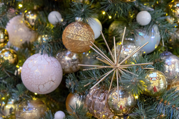 Obraz na płótnie Canvas Gold colored metallic snowflake and Christmas balls on the Christmas tree.