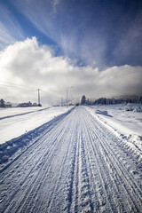 Tire tracks on a snow-covered road with a magnificent sky view