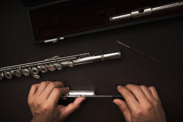 top view of a man's hands disassembling the keys of a flute to repair it. © Oscar Giraldo