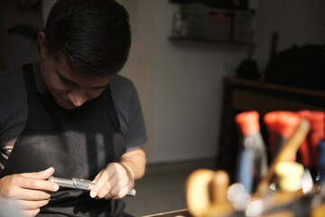Latin man checking the mouthpiece of a flute in his instrument repair shop.