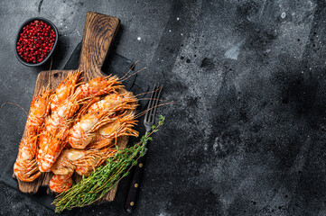 Cooked Greenland Prawn Shrimp on a wooden board. Black background. Top view. Copy space