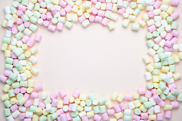 colorful frame of small marshmallows on pastel colored background with copy space
