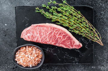 Wagyu raw sirloin steak, kobe beef meat on marble board. Black background. Top view