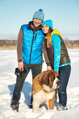 happy couple in love with St. Bernard dog in the winter - 472500614