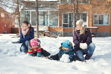 family playing with snow in the winter outdoors - 472500617