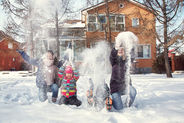 family playing with snow in the winter outdoors