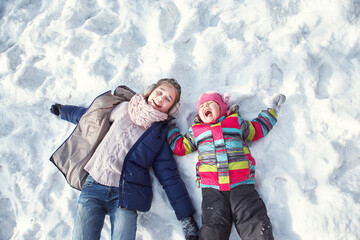 children lying on the snow in the winter outdoors - 472500620