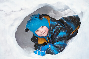 funny little boy playing in snow house - 472500624