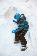 funny little boy playing in snow house