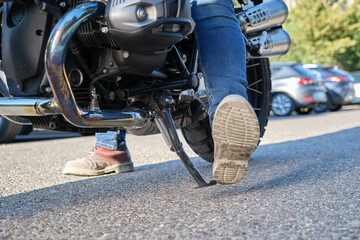 Close-up shot of motorcyclist positioning the kickstand