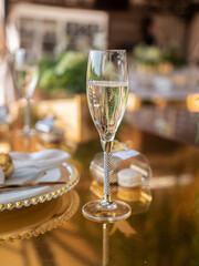 A glass of champagne and a small gift in the form of several macarons in a transparent box, on a luxurious table in a summer luxury restaurant.