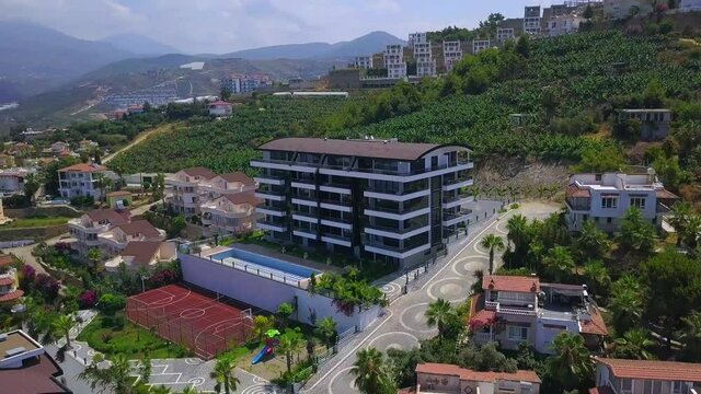 Resort view from a helicopter.Clip. A beautiful resort area with hotels, green parks, views of sports fields and large green mountains in the background