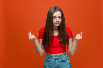 Young modern girl rubbing fingers, showing cash gesture, asking for money, reward or debt on orange...