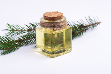 glass bottle with fir oil and a fir branch on a white background