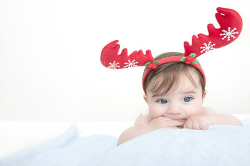 New year and Christmas concept with four month old baby boy wearing christmas antlers of a deer lying on a blue soft blanket.free text space.Holiday season.