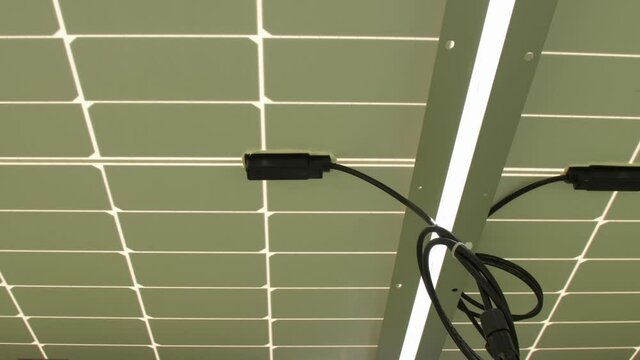 Solar cells produce energy at construction site. Black coiled cables with plugs installed on supports under panels extreme close view